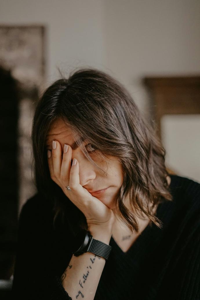 woman in black blazer covering her face